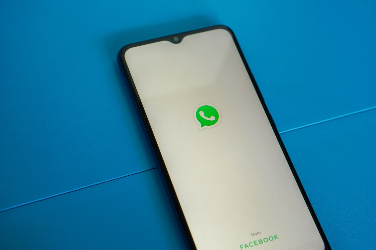 Celular sobre base azul com tela inicial do whatsapp.