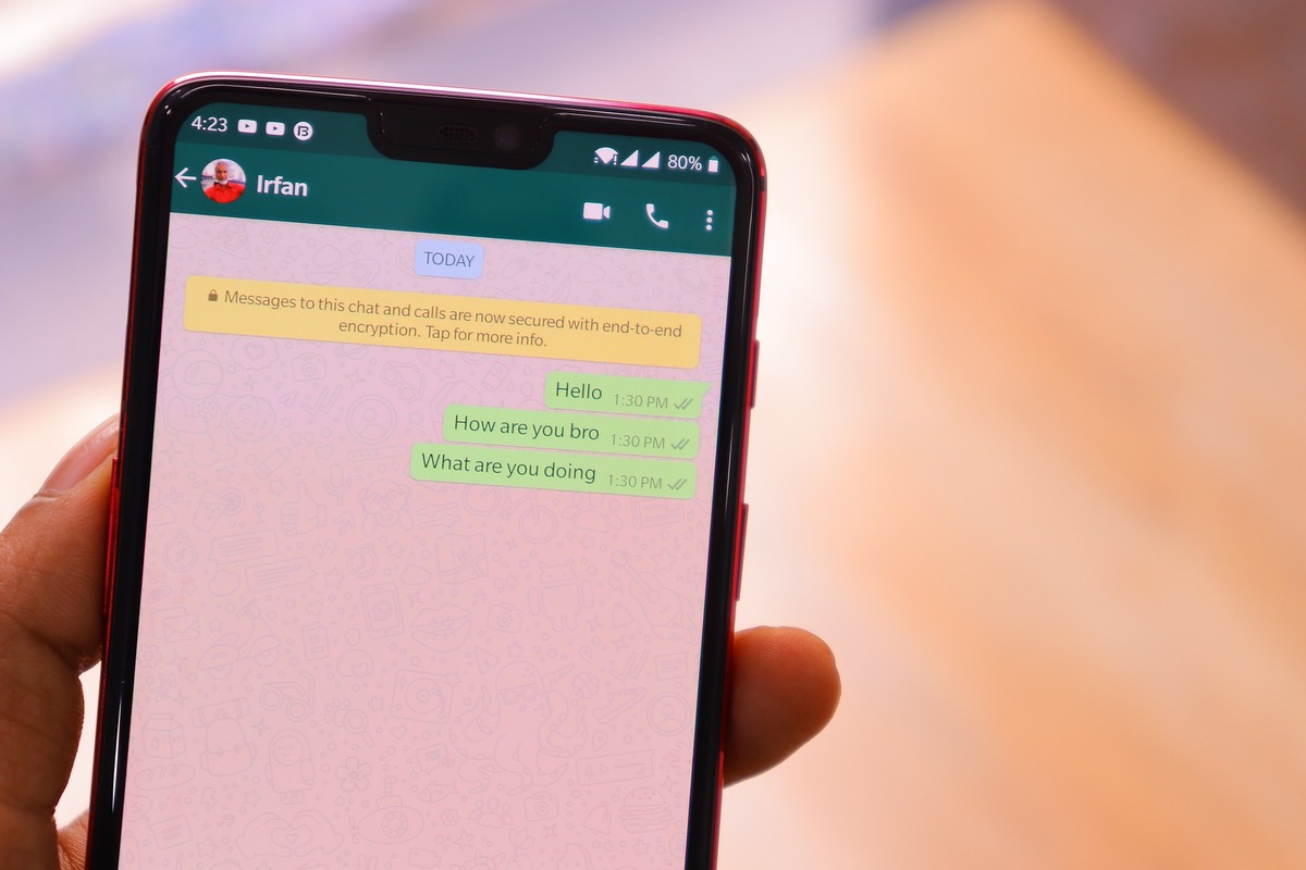 Mão feminina segura smartphone com fundo da imagem em desfoco, onde na tela ela conversa com outra pessoa pelo aplicativo whatsapp