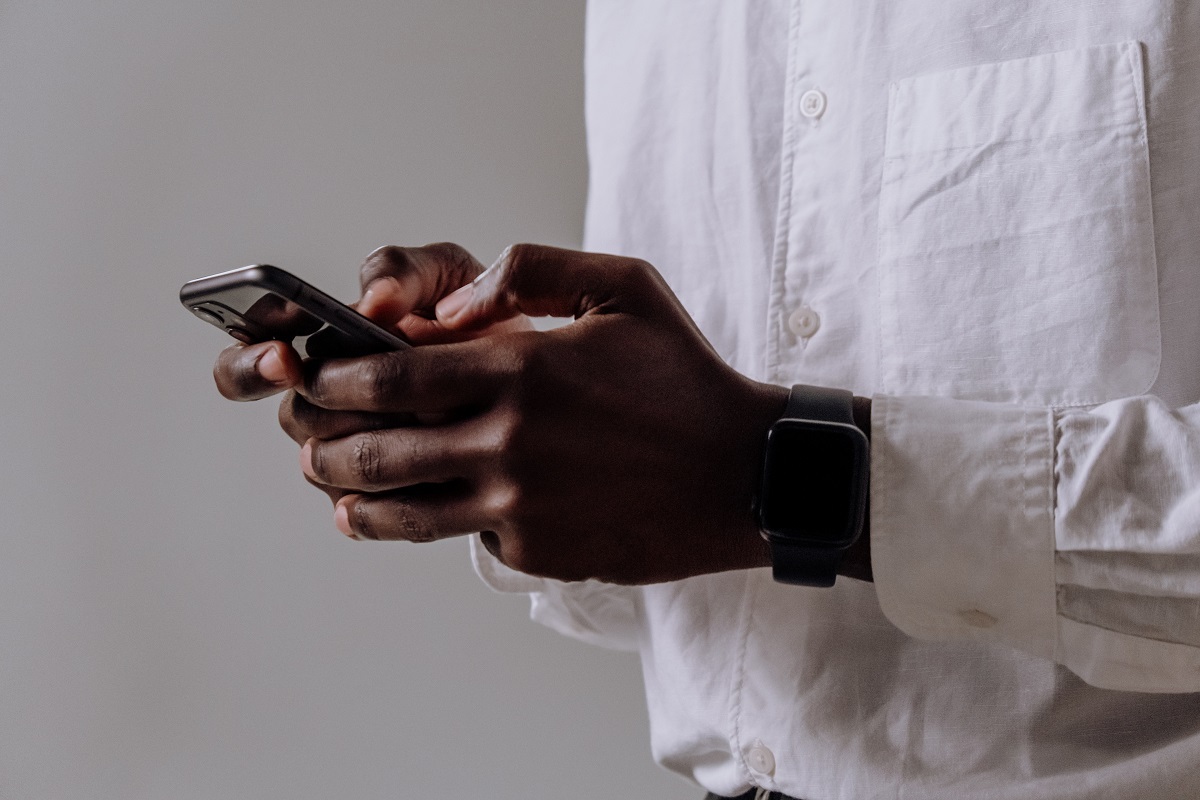 Homem segurando smartphone com as duas mãos enquanto digita algo no mesmo