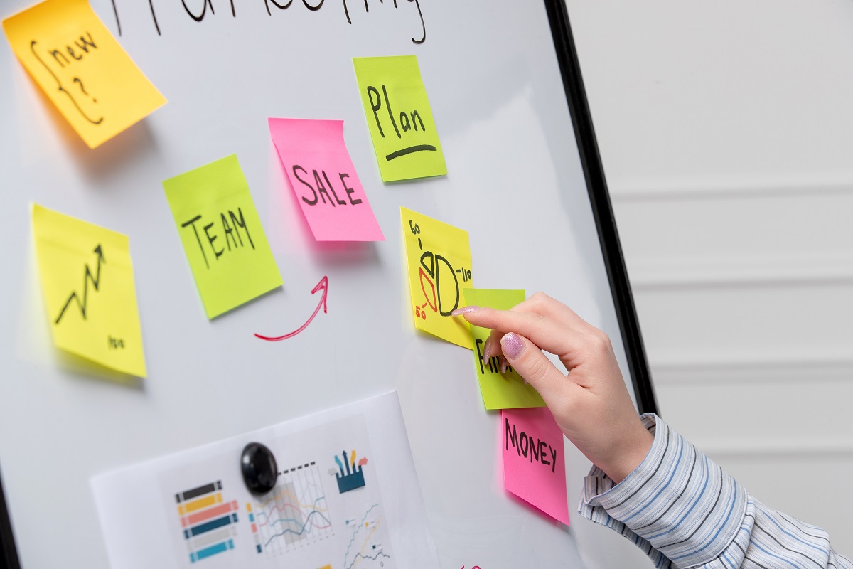 Mulher analisando post-its colados em quadro branco em escritório