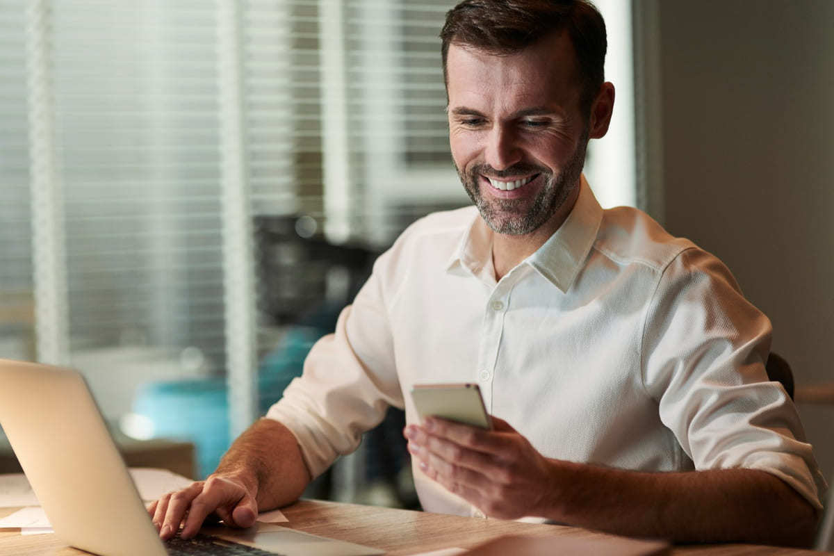 Homem com celular na mão trabalhando pois sabe Como fazer vendas online via WhatsApp